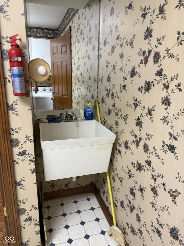 bathroom featuring baseboards, a sink, tile patterned floors, and wallpapered walls