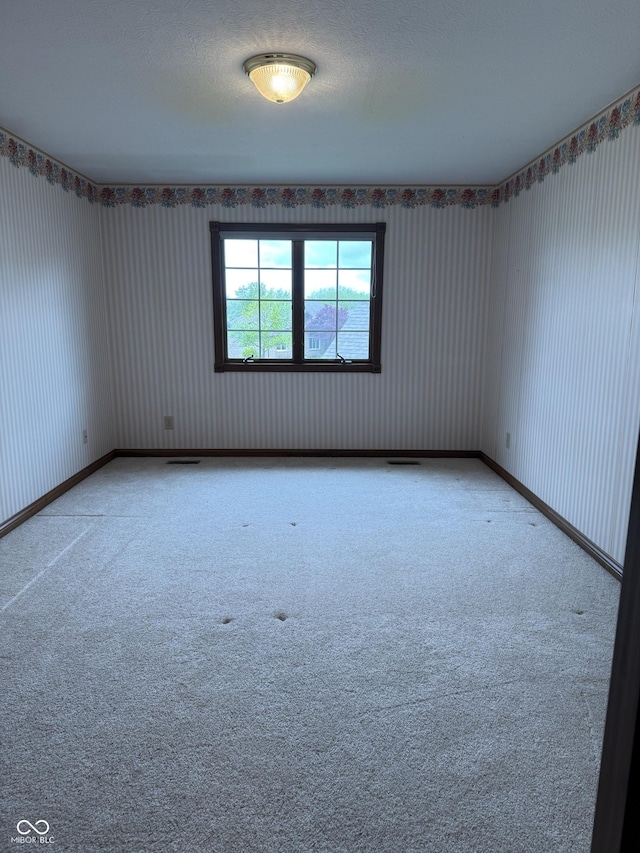 empty room with carpet floors and wallpapered walls
