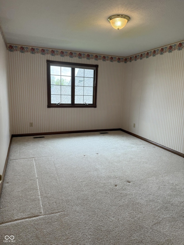 carpeted empty room with baseboards and wallpapered walls