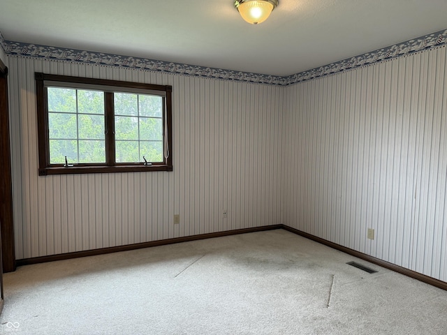 unfurnished room with visible vents, carpet, and wallpapered walls