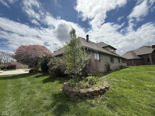view of side of property featuring brick siding and a lawn