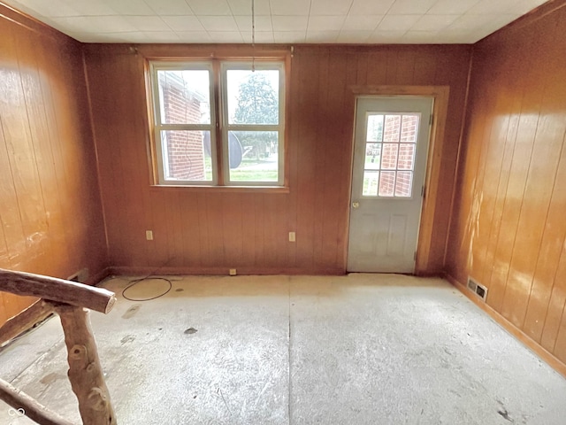 spare room with wood walls and visible vents