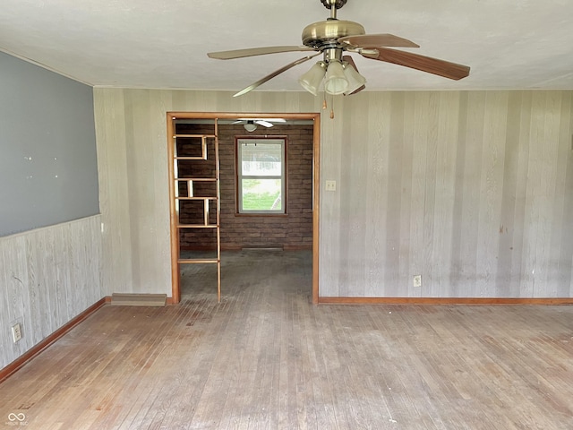 spare room with wood-type flooring, ceiling fan, and baseboards