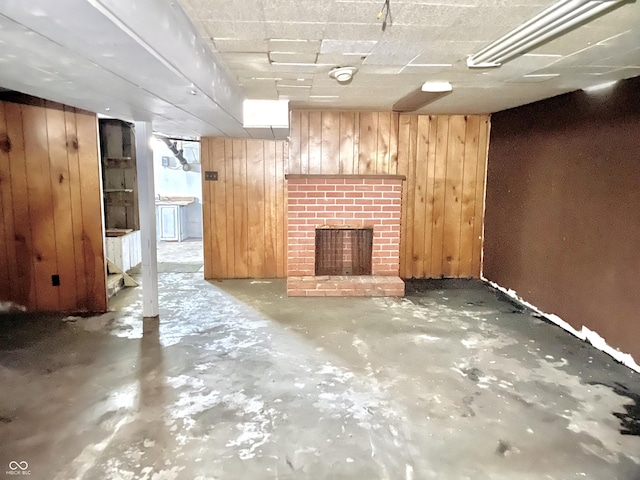 finished below grade area featuring wood walls and a brick fireplace