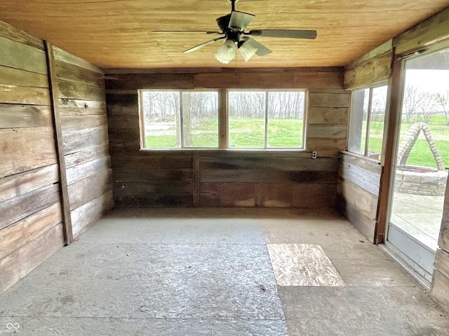 interior space featuring wooden ceiling, a ceiling fan, and wood walls