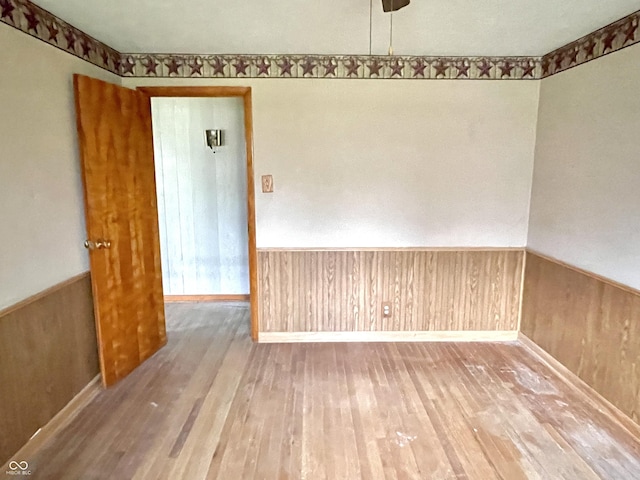 spare room with wood finished floors and a wainscoted wall