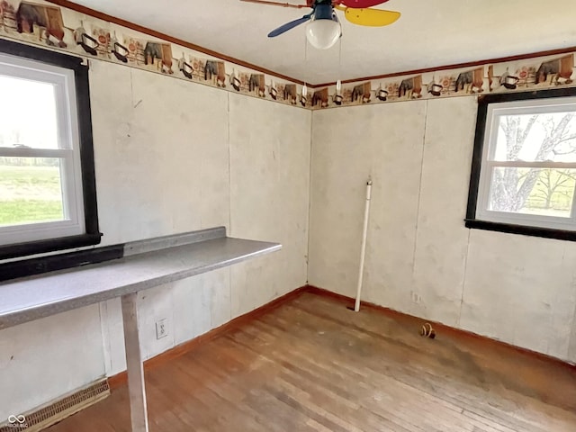 spare room featuring a ceiling fan, visible vents, a wealth of natural light, and wood finished floors