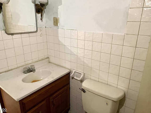 half bath featuring toilet, tile walls, and vanity