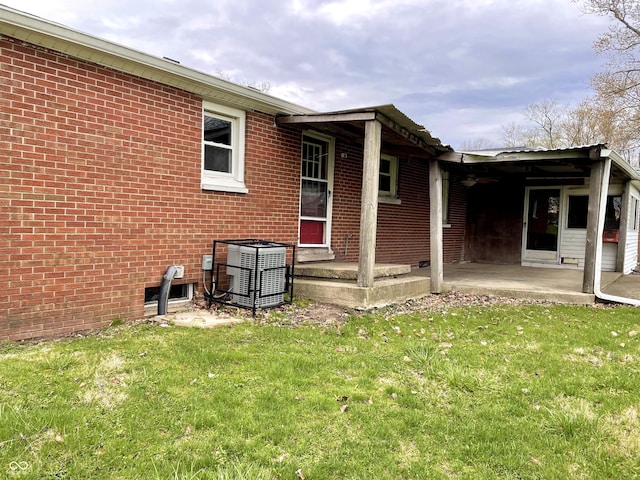back of house featuring central AC unit, a yard, a patio area, and brick siding