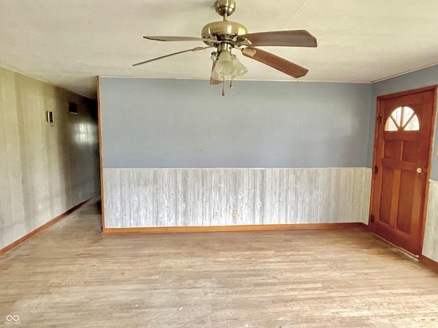 entrance foyer featuring baseboards, wainscoting, ceiling fan, and wood finished floors