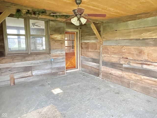 empty room with a ceiling fan and wood walls