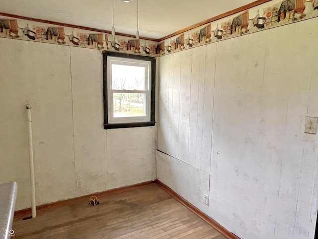 empty room with light wood-style flooring and wooden walls