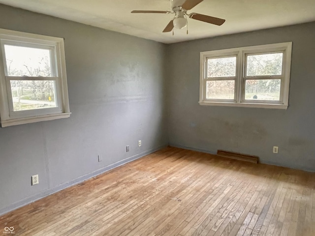 spare room with ceiling fan, baseboards, plenty of natural light, and hardwood / wood-style floors