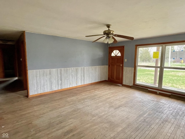interior space with ceiling fan, wainscoting, and wood finished floors