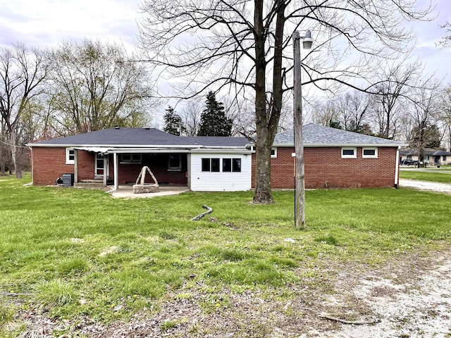 back of house with a yard, brick siding, and a patio