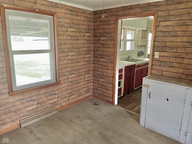 unfurnished dining area with visible vents, a sink, wood finished floors, and wood walls