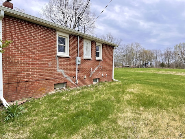 view of home's exterior featuring a yard, brick siding, and a chimney