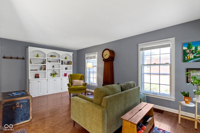 living room featuring wood finished floors, a healthy amount of sunlight, baseboards, and visible vents
