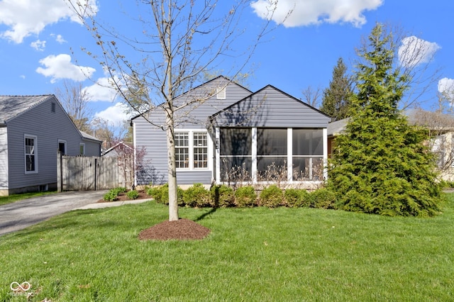 bungalow featuring a sunroom, a front yard, and fence