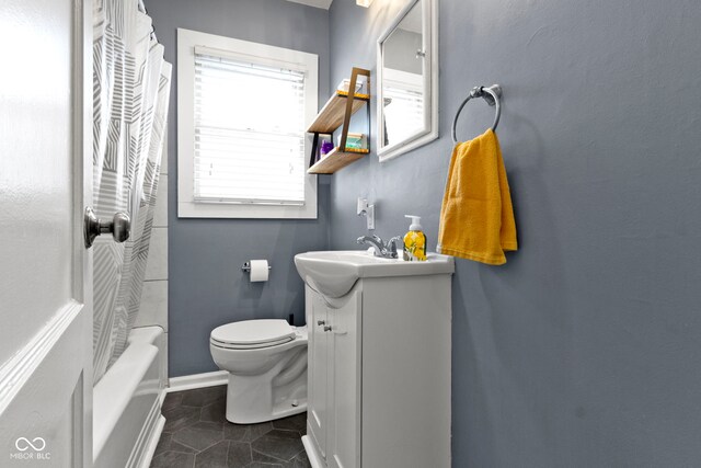 bathroom with tile patterned flooring, toilet, vanity, shower / bath combo with shower curtain, and baseboards