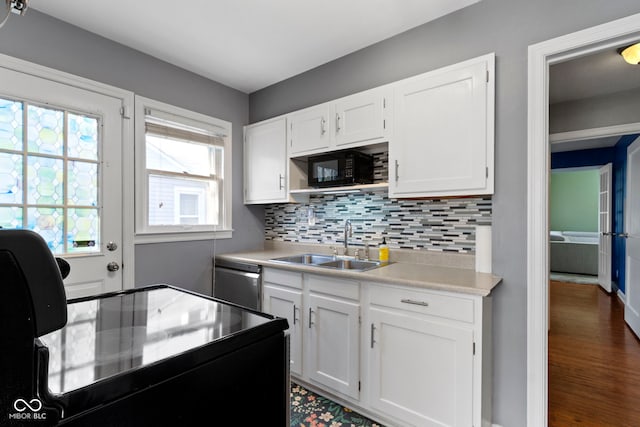 kitchen featuring white cabinets, stainless steel dishwasher, a sink, and tasteful backsplash