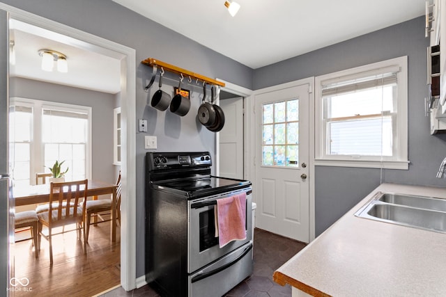kitchen with stainless steel electric stove, light countertops, and a sink