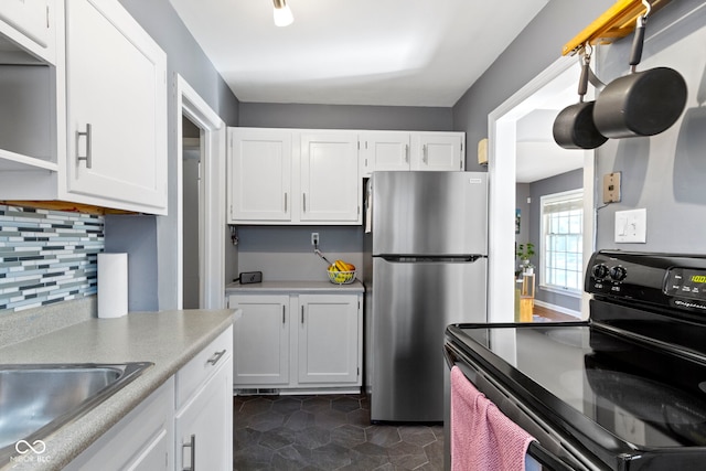 kitchen with white cabinets, electric range, freestanding refrigerator, backsplash, and light countertops