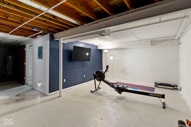 exercise area featuring water heater and concrete block wall