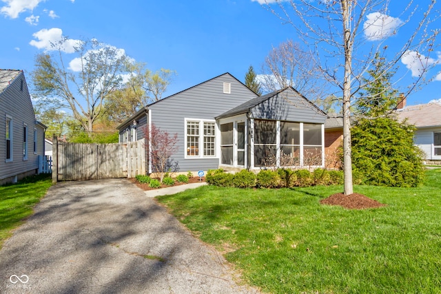 view of front of home featuring a front lawn, a gate, fence, a sunroom, and aphalt driveway