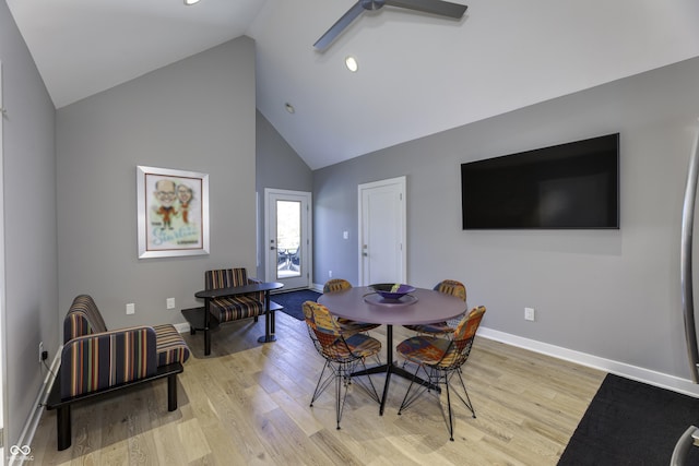 dining space featuring a ceiling fan, high vaulted ceiling, baseboards, and light wood finished floors