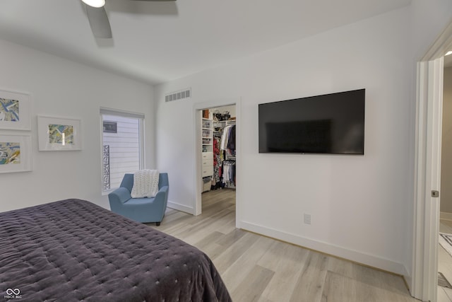 bedroom with visible vents, a closet, baseboards, a walk in closet, and light wood finished floors