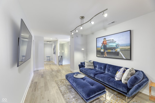 living area with baseboards, light wood-style flooring, and visible vents