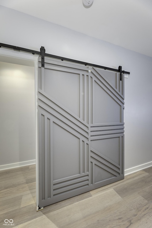 room details featuring baseboards, a barn door, and wood finished floors