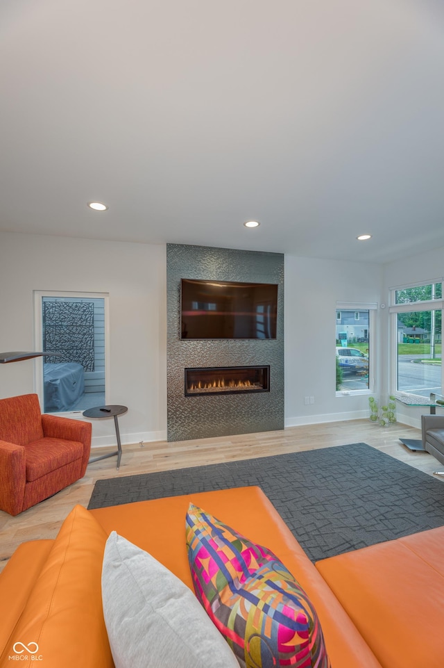 living area featuring a large fireplace, baseboards, recessed lighting, and wood finished floors