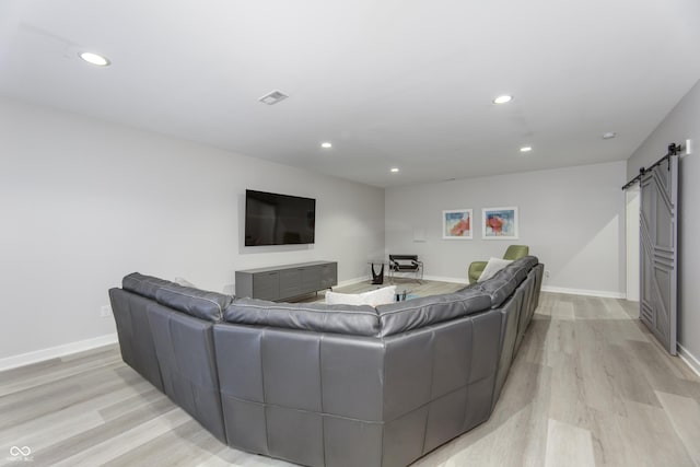 living area with recessed lighting, a barn door, light wood finished floors, and baseboards