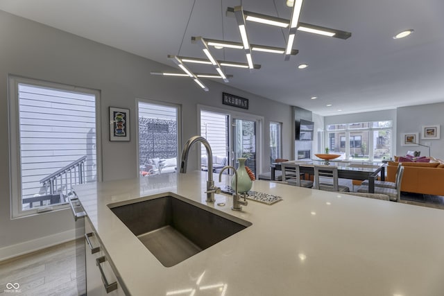 kitchen featuring a sink, light countertops, recessed lighting, open floor plan, and light wood-type flooring