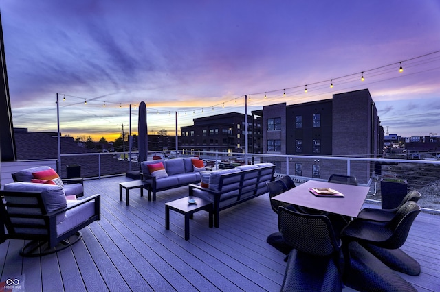 deck at dusk featuring outdoor dining area and an outdoor living space