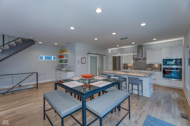 dining area with recessed lighting, a barn door, light wood-style flooring, and baseboards
