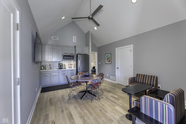 dining room featuring ceiling fan, bar, high vaulted ceiling, baseboards, and visible vents