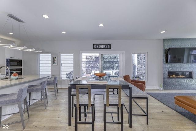 dining room with a fireplace, recessed lighting, baseboards, and light wood-style floors