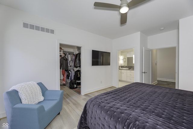 bedroom with a walk in closet, visible vents, baseboards, a closet, and light wood-style floors