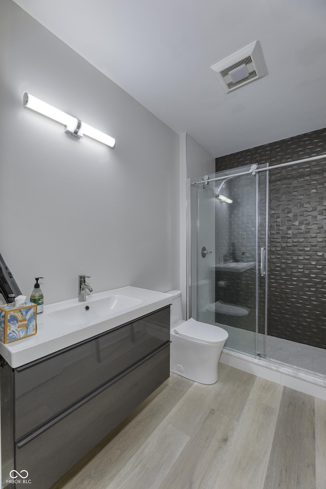 full bath featuring visible vents, a shower stall, wood finished floors, vanity, and toilet