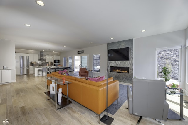 living room with recessed lighting, light wood-style floors, and a tile fireplace