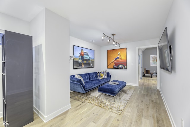 living area featuring baseboards and light wood finished floors