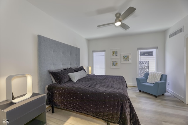 bedroom with ceiling fan, wood finished floors, and visible vents
