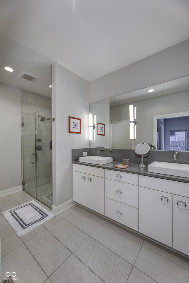 full bathroom featuring a sink, double vanity, baseboards, a shower stall, and visible vents