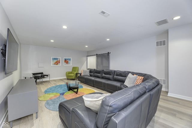 living room with recessed lighting, visible vents, a barn door, and light wood finished floors