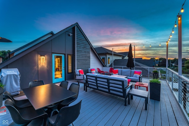 deck at dusk featuring outdoor dining space, an outdoor living space, and area for grilling