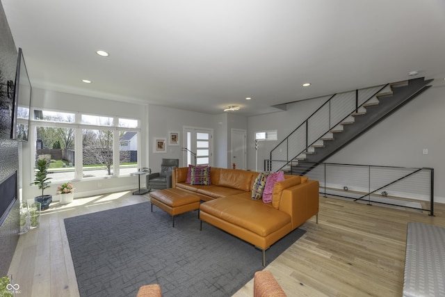 living area featuring stairs, recessed lighting, a large fireplace, and hardwood / wood-style floors