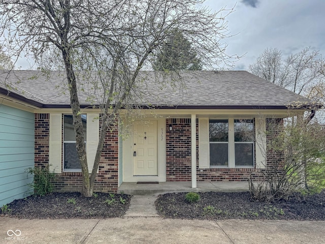 9362 Helmsdale Dr, Indianapolis, IN 46256 - view of exterior entry with a porch, a shingled roof, and brick siding